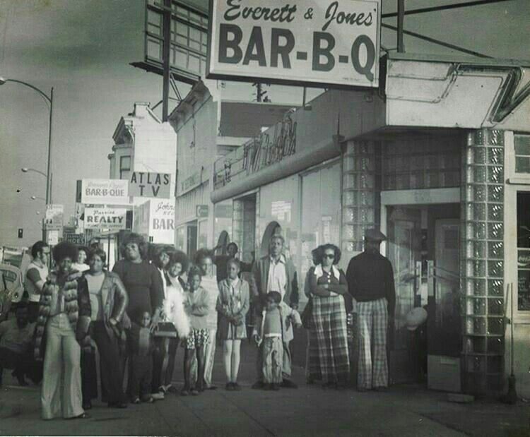 A historical black-and-white photo showing a group of people standing outside Everett & Jones' Bar-B-Q.