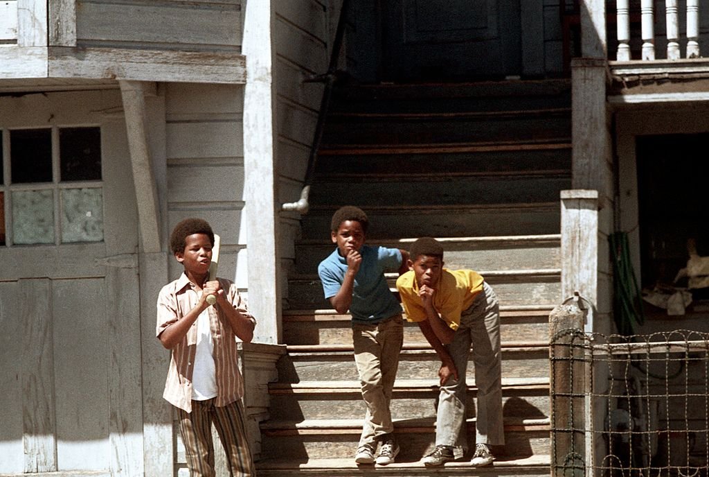 A nostalgic black-and-white photo of three boys standing on a porch, having fun and playing together.